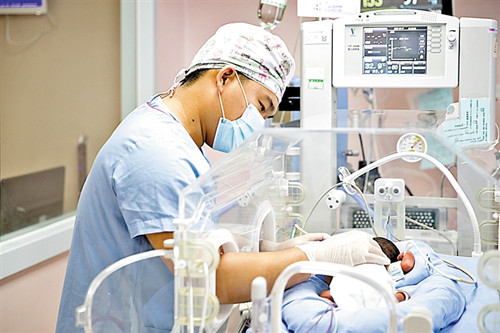 宝安区妇幼保健院，护士在新生儿重症监护室照看保温箱里的婴儿